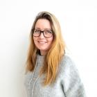 Bilde av forfatteren som er en kvinne. Hun har langt blondt hår og briller