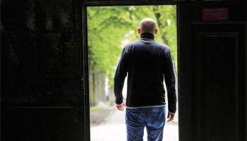 Bildet av forsiden på rapport om karriereveiledning i kriminalomsorgen. Mann som står med ryggen til i en døråpning.