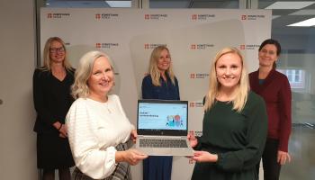 Fem kvinner samlet rundt en bærbar pc.