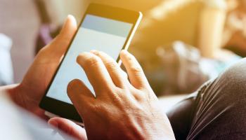 Bilde av en mobiltelefon der man ser kun hendene som taster på mobilen