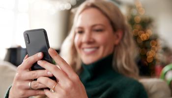 Blond dame som ser på mobiltelefonen og smiler