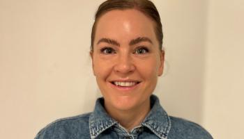 Bilde av smilende, mørkhåret ung dame i dongeriskjorte