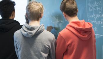 Bilde av tre gutter som står foran en tavle