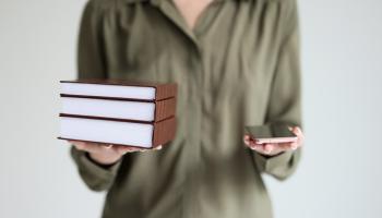 En person som holder noen bøker og en telefon