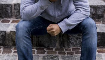 Ungdom med hetteganser som sitter i trapp