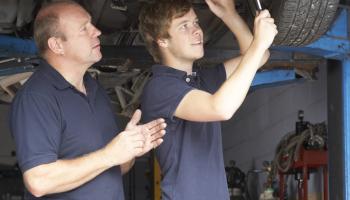 en gutt som lærer av en bilmekaniker