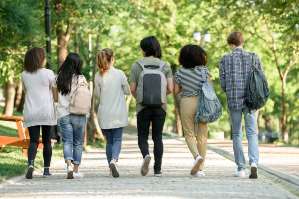 Bildet viser ryggen på unge mennesker som går bortover en vei