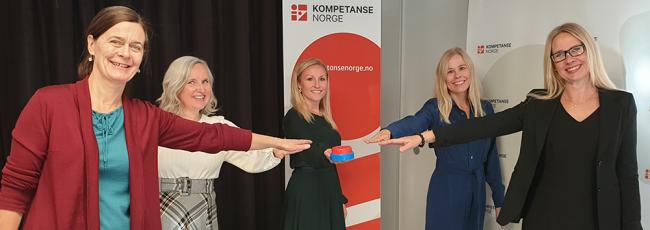 Fem kvinner strekker ut hånda for å trykke på knapp.