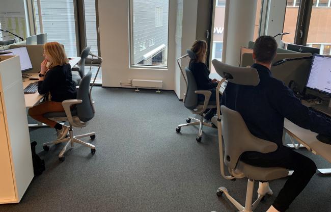 Tre karriereveiledere sitter ved skrivebordet sitt og jobber.