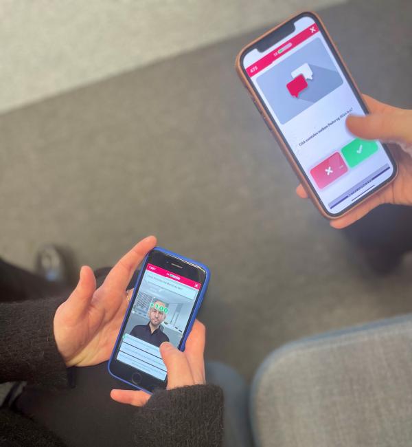 Bilde av to mobiler med hender, på skjermen vises spillet GodKollega