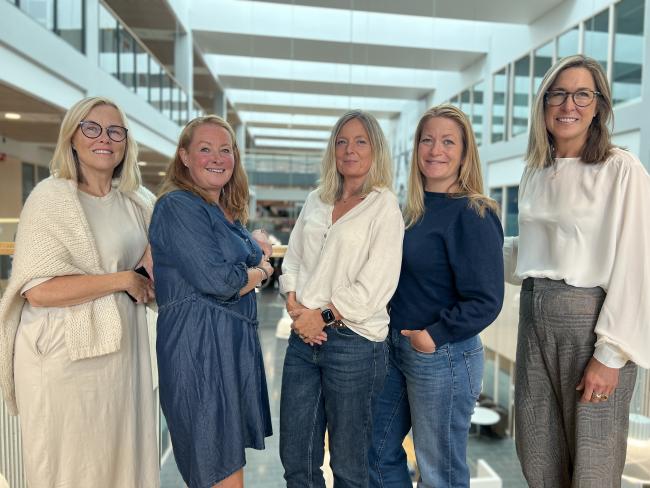 Fem personer som står og ser i kamera