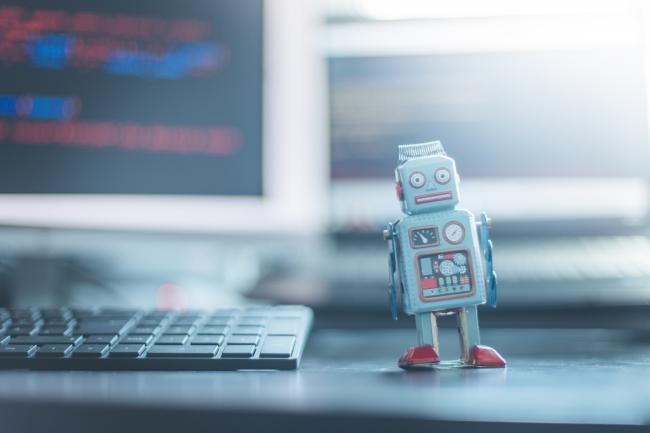 Bilde av en liten robot ved siden av en PC