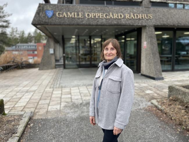 Foto av dame med grå byggnad i bakgrunnen