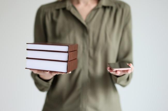 En person som holder noen bøker og en telefon