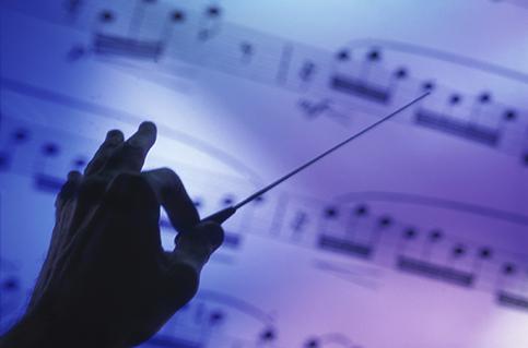 Silhouette of a hand conducting over sheet music